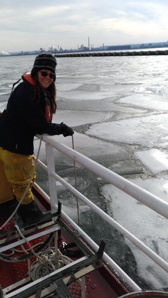 Biologist deploying a sampling rope off a ship rail amongst large rafts of ice.