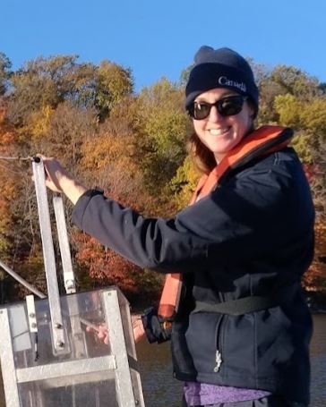 Heather deploying a schindler trap off a small boat with fall leaves in the background.