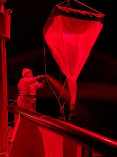 washing down large net off side of ship under red light