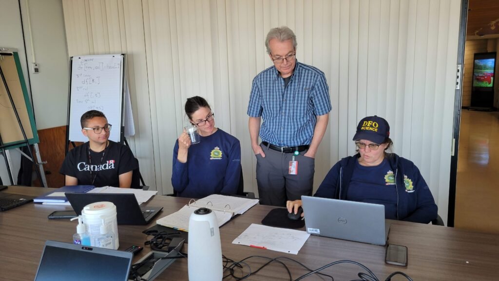 Four science staff are working around a computer in a board room. 