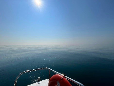 Images of water from a boat. A large research building in the background, the wake of a boat at speed with a bridge in the background, and flat calm water of a lake with no horizon. 